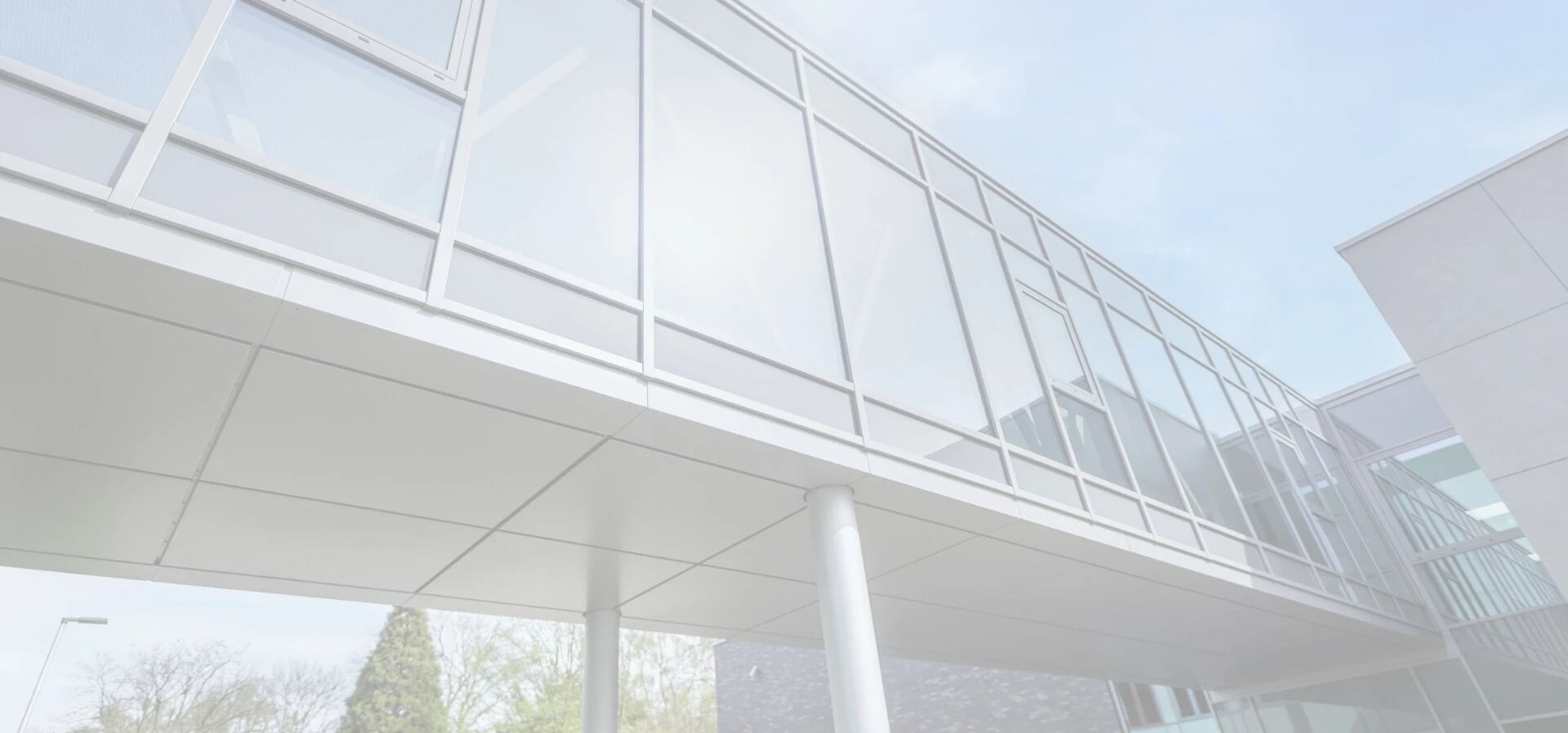 Moderne Architektur mit Glasfenstern und einer überdachten Brücke.