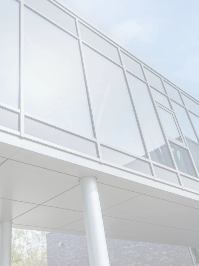 Moderne Architektur mit Glasfenstern und einer überdachten Brücke.